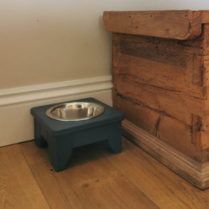 Handmade wooden dog bowl stand painted in hague blue next to a wooden box against a white wall