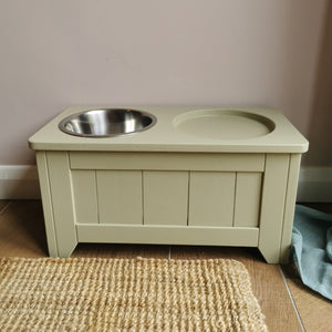 handmade raised wooden enrichment stand painted in farrow and ball shade ball green with a space for an enrichment feeding bowl and a stainless steel water  bowl